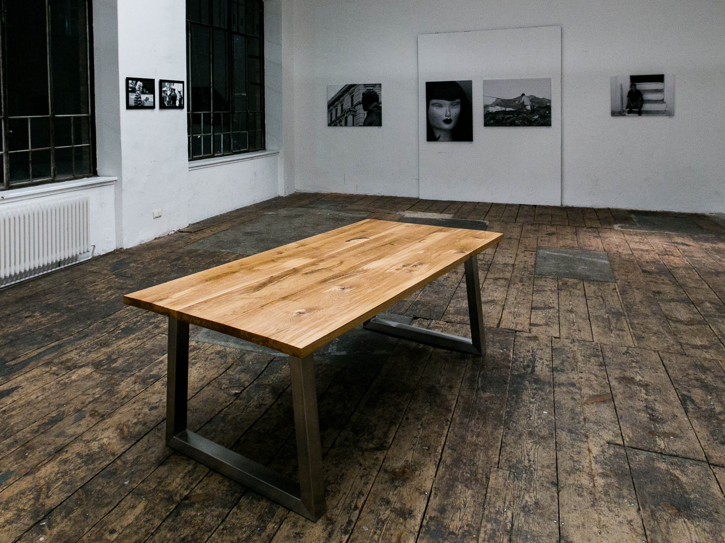 Ein Massivholztisch mit Eichenplatte auf einem Nirostagestell. Ausgestellt in einer Fabrikshalle im Zuge einer Fotovernissage.